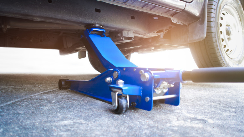 A blue floor jack holding up a car.