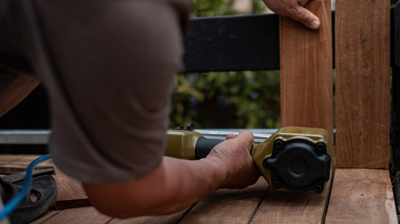 Man attaching fence with finish nailer