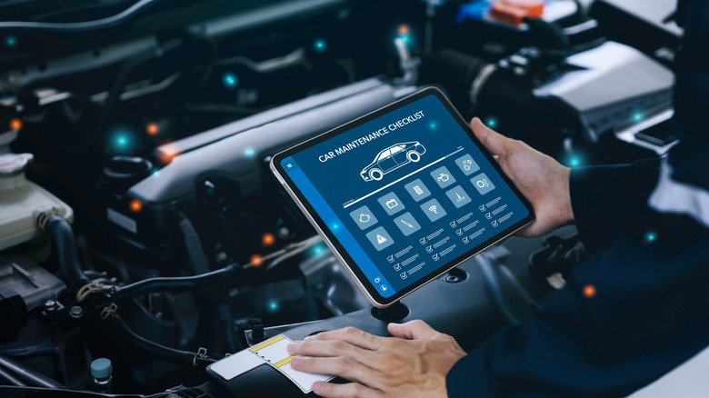 Hand of a mechanic holding the tablet for maintenance checklist vehicle