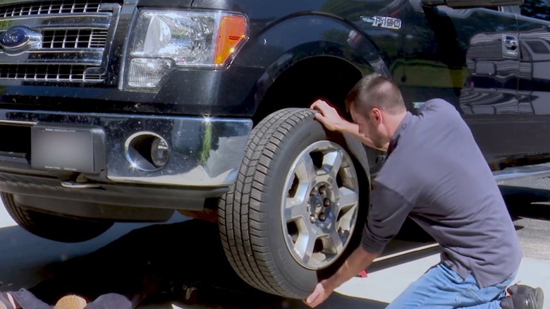 A man checs for wheel bearing play