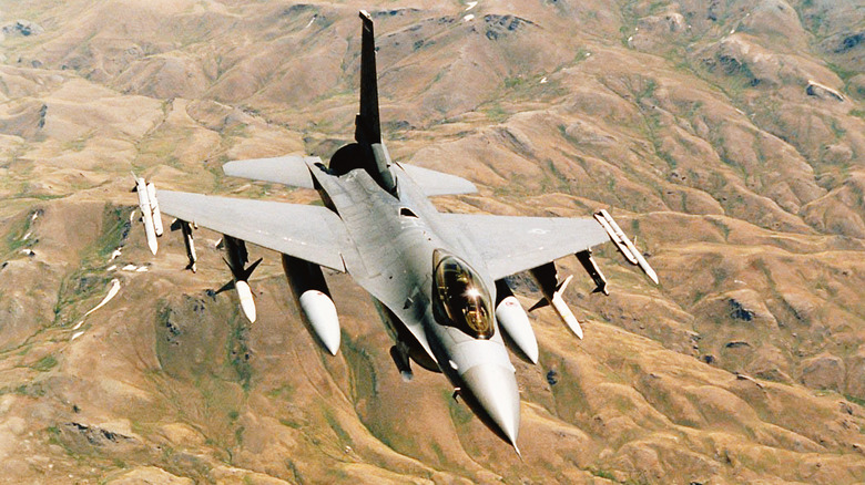 An F-16 Fighting Falcon flying over mountainous terrain