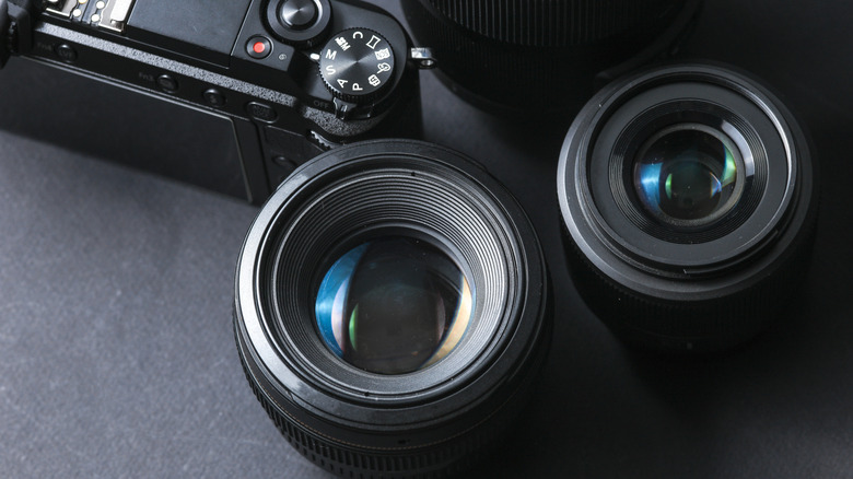 Camera lenses sitting beside a camera.