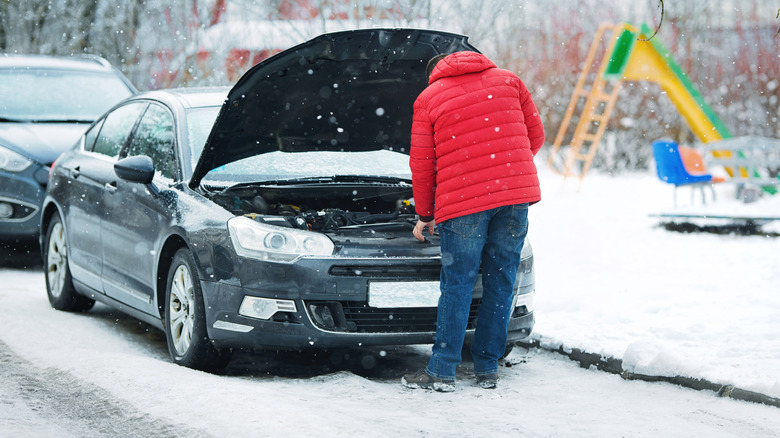 Checking under a car hood in the winter