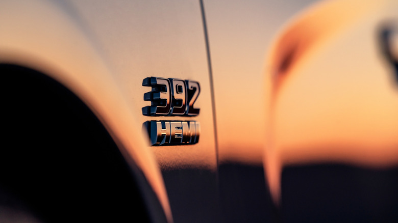 A 392 HEMI engine badge on the side of a silver 2023 Dodge Charger at sunset