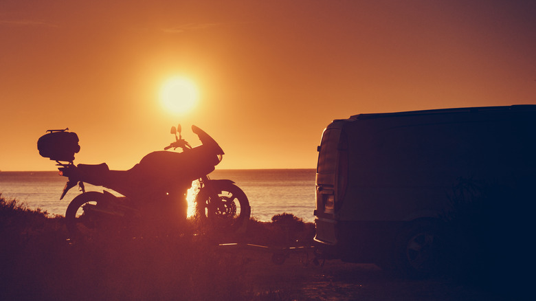 motorcycle and small camper at sunset