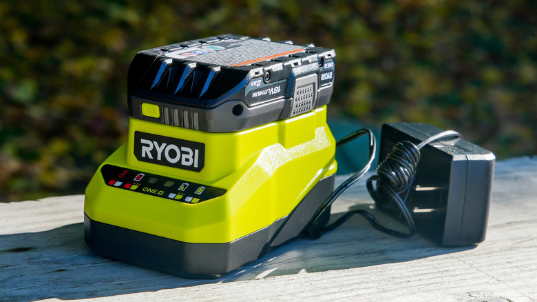 A Ryobi battery on a Ryobi charger outside.