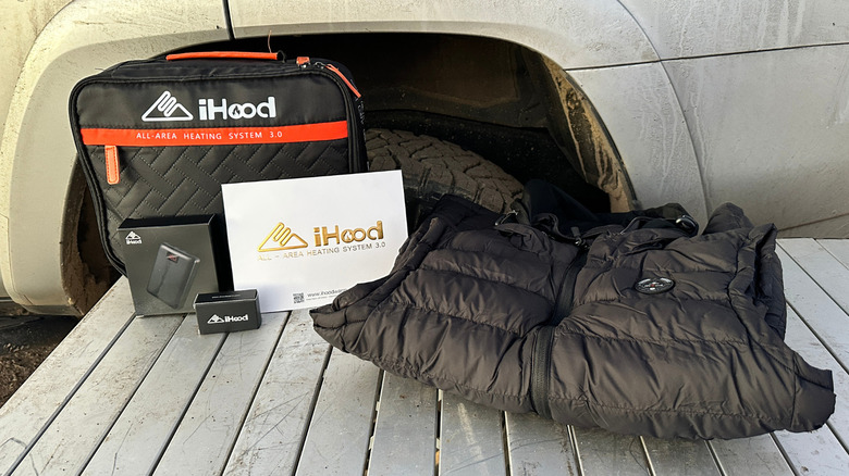 Black heated vest, battery pack, and case on a metal table