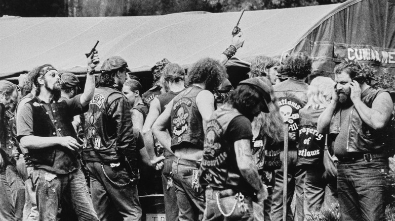 Members of the Outlaws motorcycle gang fire pistols in the air at the funeral of a slain leader.