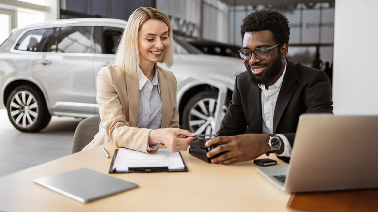 Woman making a payment with a credit card in a car dealership