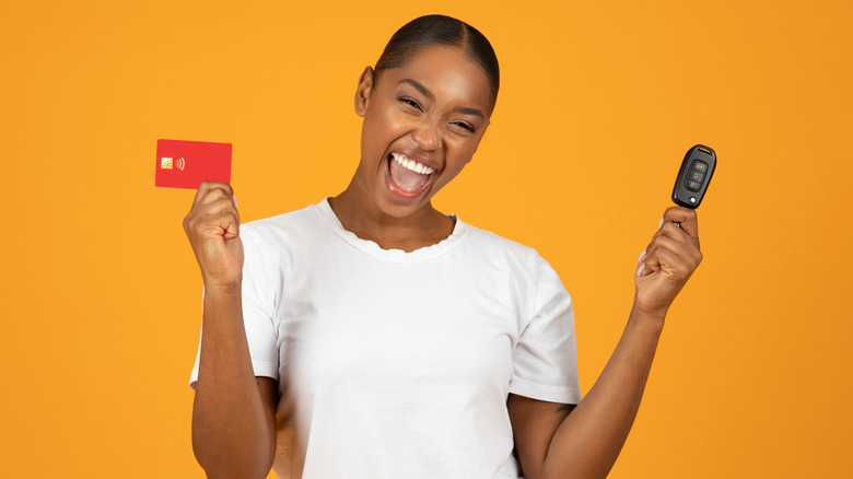 Woman smiling with car fob and credit card in hands