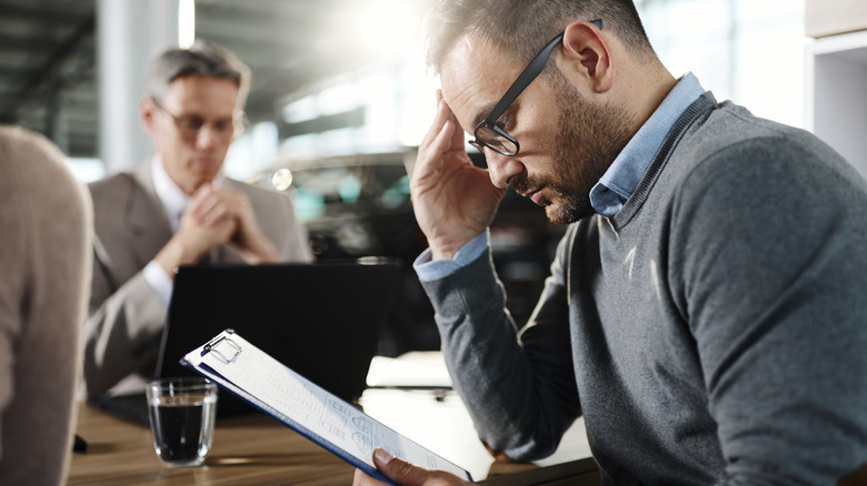 Man thinking about car purchase in car dealership