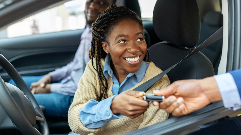 Young woman in car getting keys