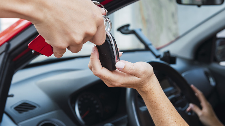 Dealership handing keys to new driver in car