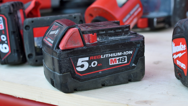 Milwaukee batteries on a wood table.