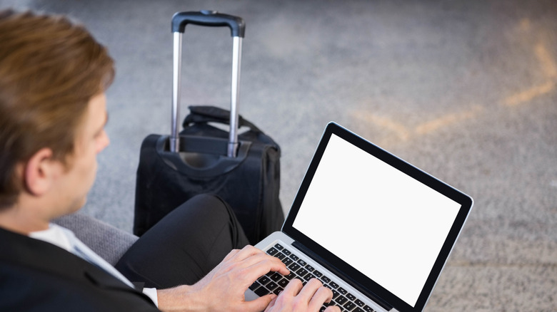 Man using his laptop after getting through TSA with his carry-on bag