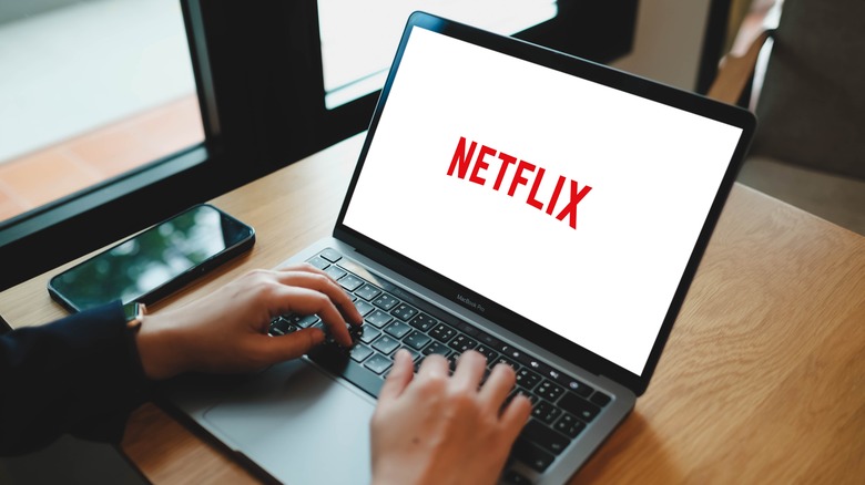 Hands resting on laptop showing Netflix logo.