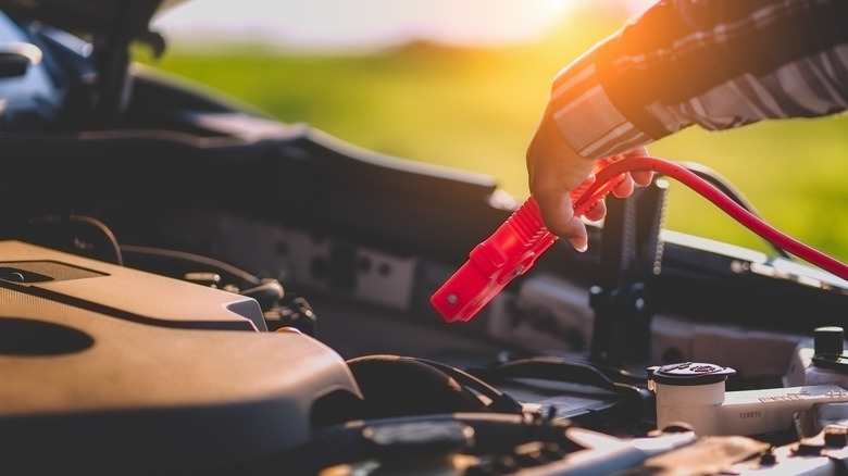 An auto mechanic gives a car battery a jump