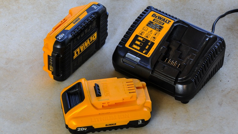 DeWalt batteries and a charger on a concrete floor.