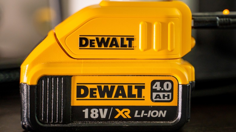 A yellow DeWalt battery plugged into a charger.