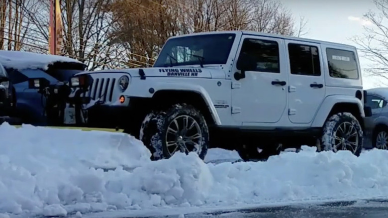 A white 2014 Jeep Wrangler Sahara plows snow