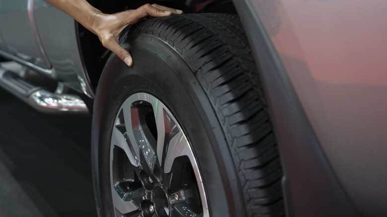 A hand holding onto a car's tire.