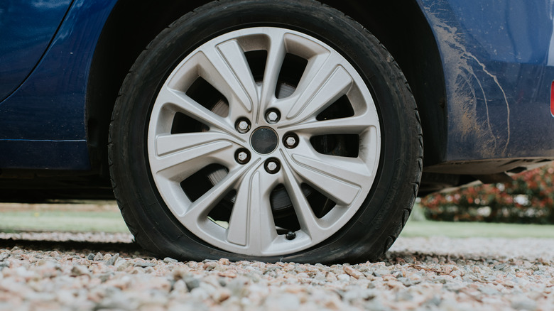 A blue car with a flat tire.