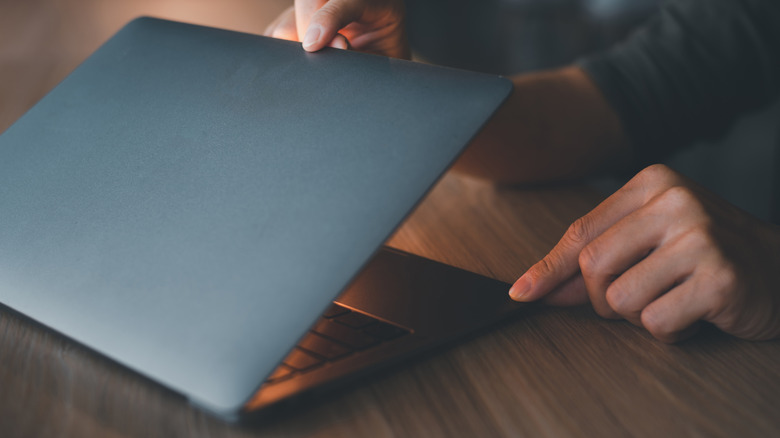 Person closing a laptop's lid