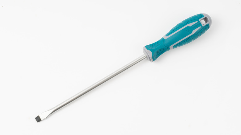 A flathead screwdriver with a teal handle placed on a white surface