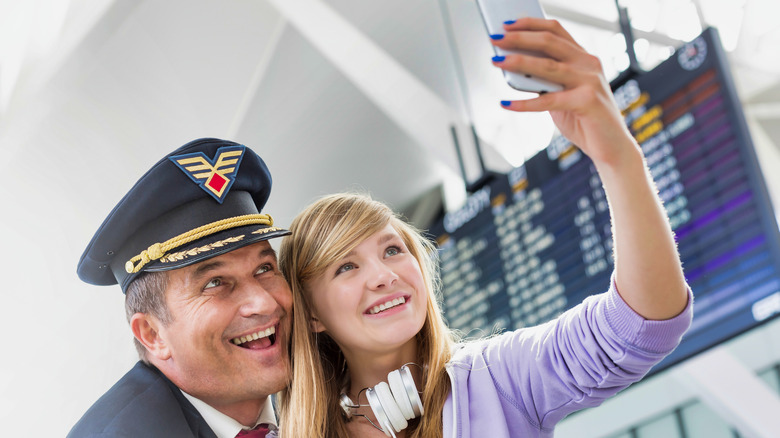 Girl taking selfie with a pilot in airport