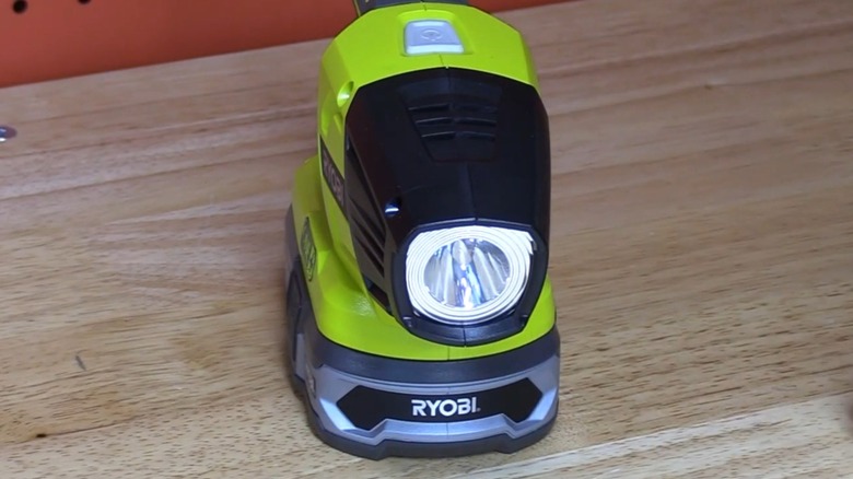 A Ryobi flashlight powered up on a table.