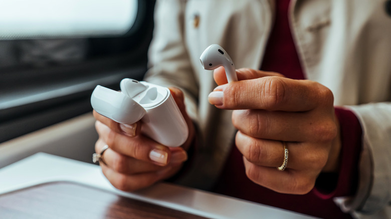 Woman's hands taking an AirPod out of the charging case