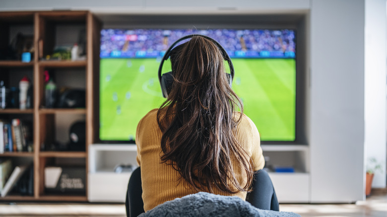 Woman watching TV using wireless headphones 