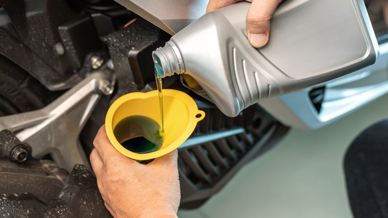 pouring motorcycle oil into engine