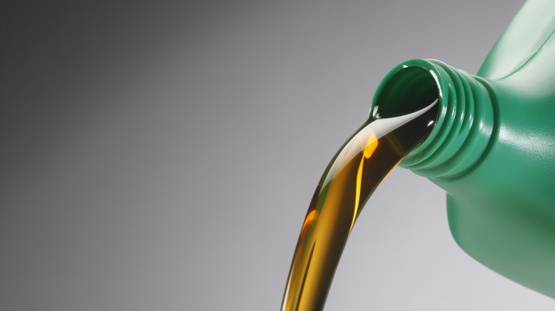 motor oil being poured out of green container