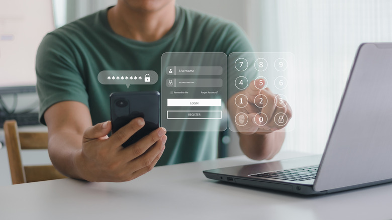 A man uses a second form of authorization on his phone, typing into a digitally generated keypad above his laptop