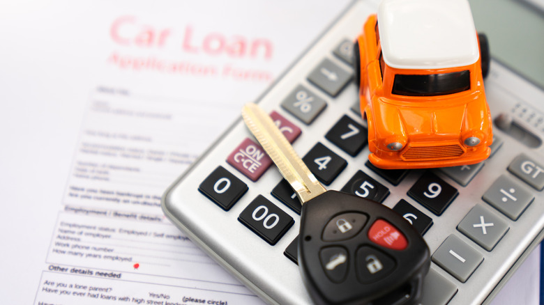 Stock image of a car key on a car loan agreement