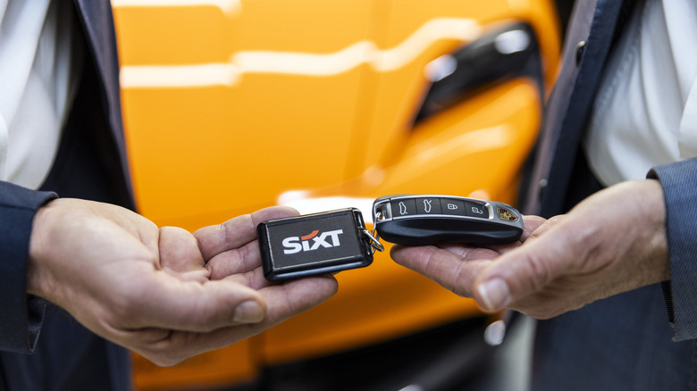 Two hands holding Sixt keychain and key fob