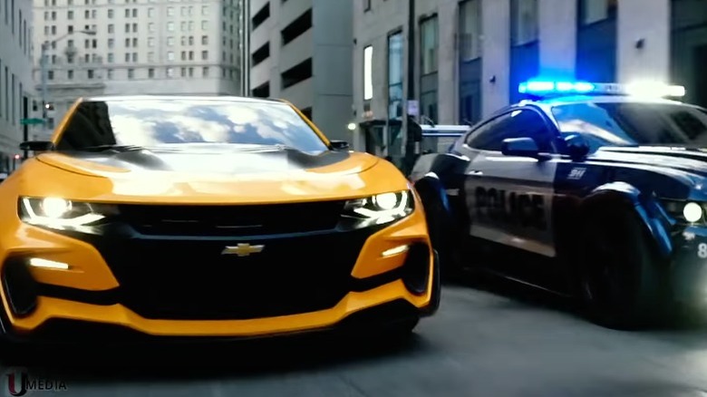 Yellow (Bumblebee) Camaro driving beside a Ford Mustang