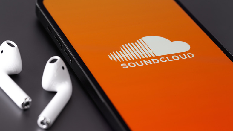 Soundcloud app on a smartphone with earbuds next to the phone