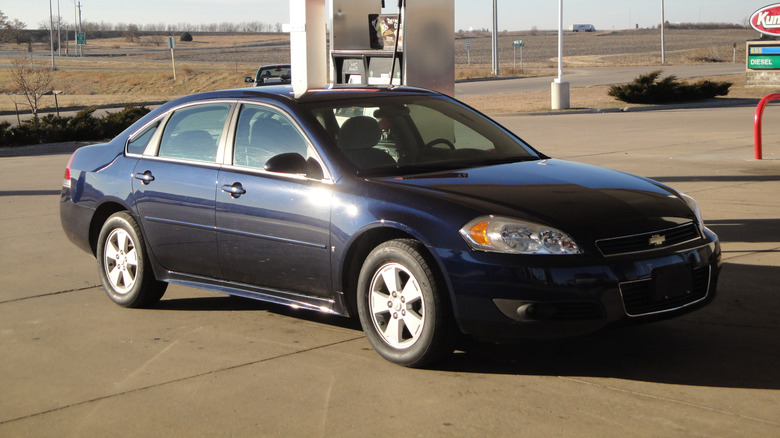 A dark blue ninth generation Chevrolet Impala at a gas station, front 3/4 view