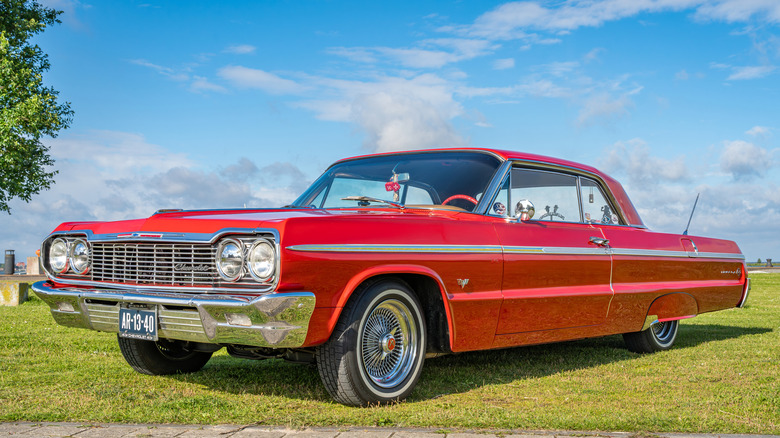 A 1964 Chevrolet Impala Sports Coupe in red, front 3/4 view, whitewall tires with wire wheels