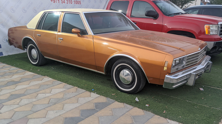 A late-'70s Chevrolet Impala in orange, white roof, front 3/4 view