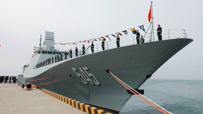 Naval servicemen stand aboard the 0545B frigate at its commissioning ceremony.