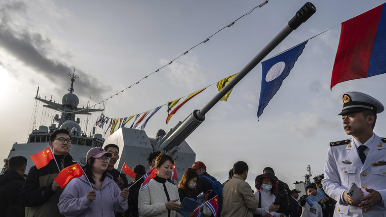 Celebrants stand before a cannon on a Chinese destroyer.