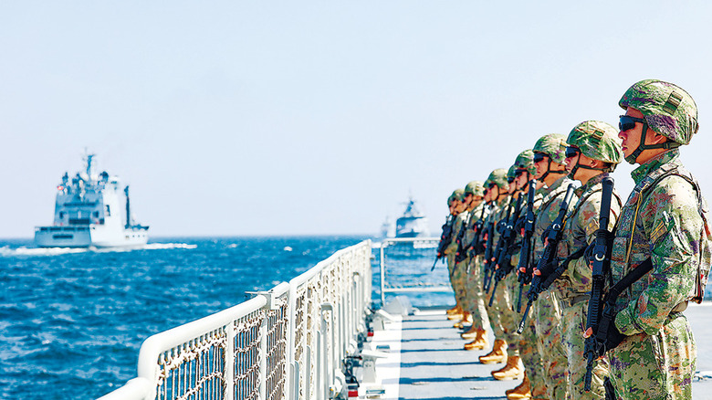 Servicemen stand at attention aboard a Chinese vessel.