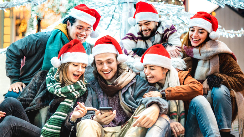 A group of happy friends gather around a cell phone