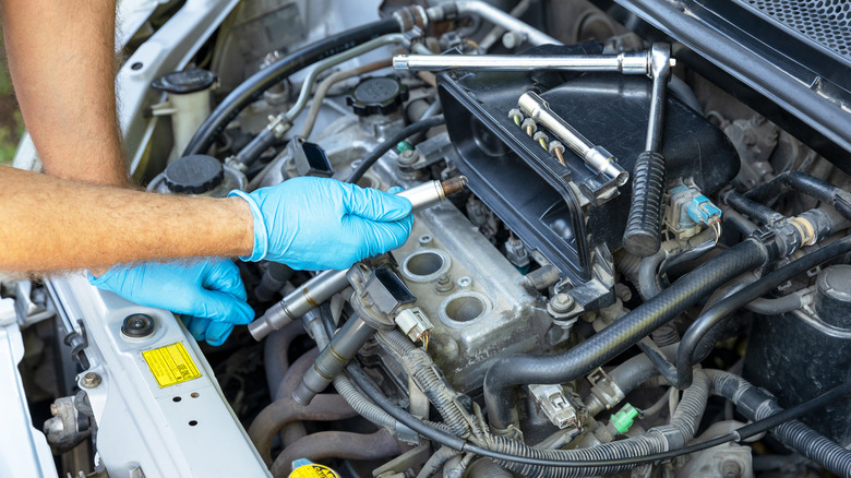 Hand removing car spark plugs