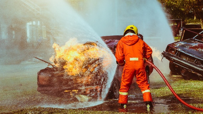 Fire fighter putting out fire on a car