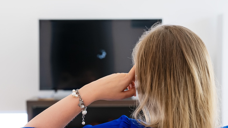 A woman sitting in front of a TV showing loading screen