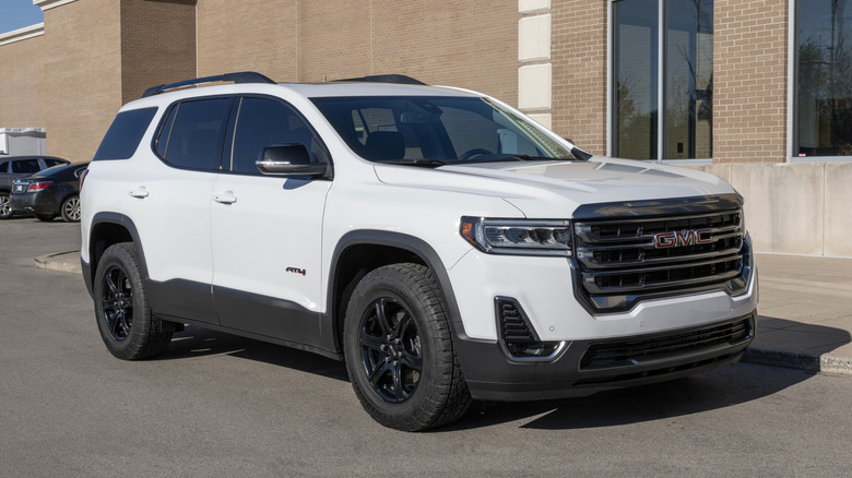 A white GMC Acadia parked outside on the street.